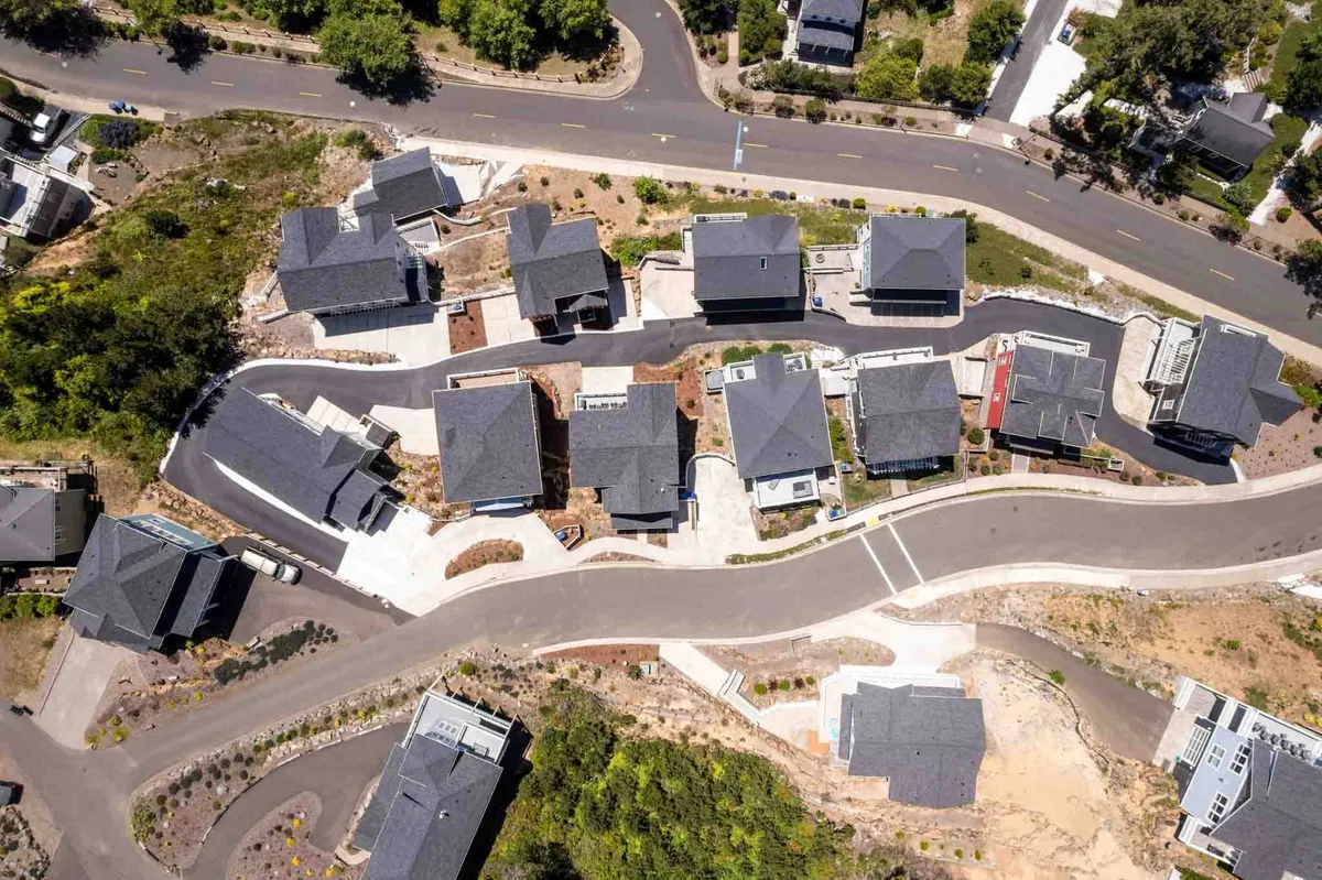 A wide-angle view of a cluster of modern homes arranged along a gently curving roadway. Landscaped areas, communal paths, and open green spaces invite outdoor gatherings, leisure walks, and community events—perfect for families seeking exploration and play.