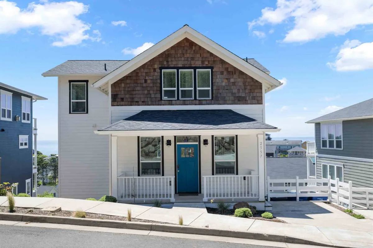 A welcoming exterior shot of the property’s front door, highlighted by its striking blue color, symmetrical windows, and landscaped garden. The inviting porch and thoughtfully kept outdoor space create a sense of homecoming after a day of coastal activities.