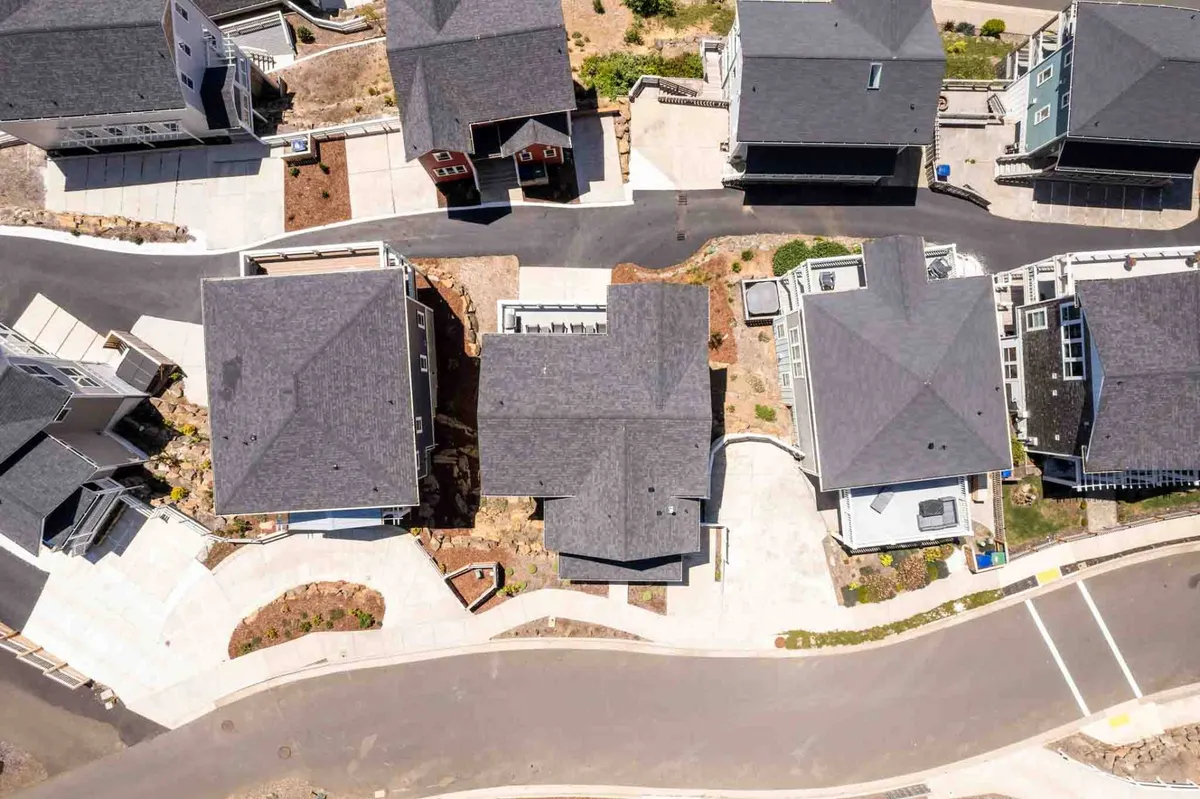 An aerial view of the neighborhood showcases the rooftops of houses, curved streets, and thoughtful landscaping. The layout hints at walkable streets and communal spaces, highlighting the property’s integration within an active, inviting community.