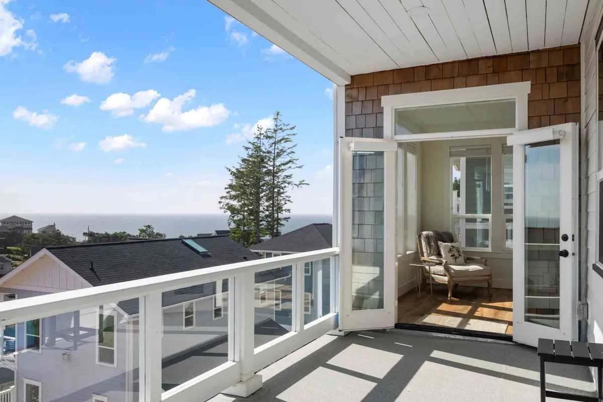 This image displays an open balcony with a comfortable chair and a stunning view of the ocean, inviting guests to relax and soak in the natural coastal beauty. The tranquil setting evokes the serenity and retreat-like atmosphere referenced in the section.