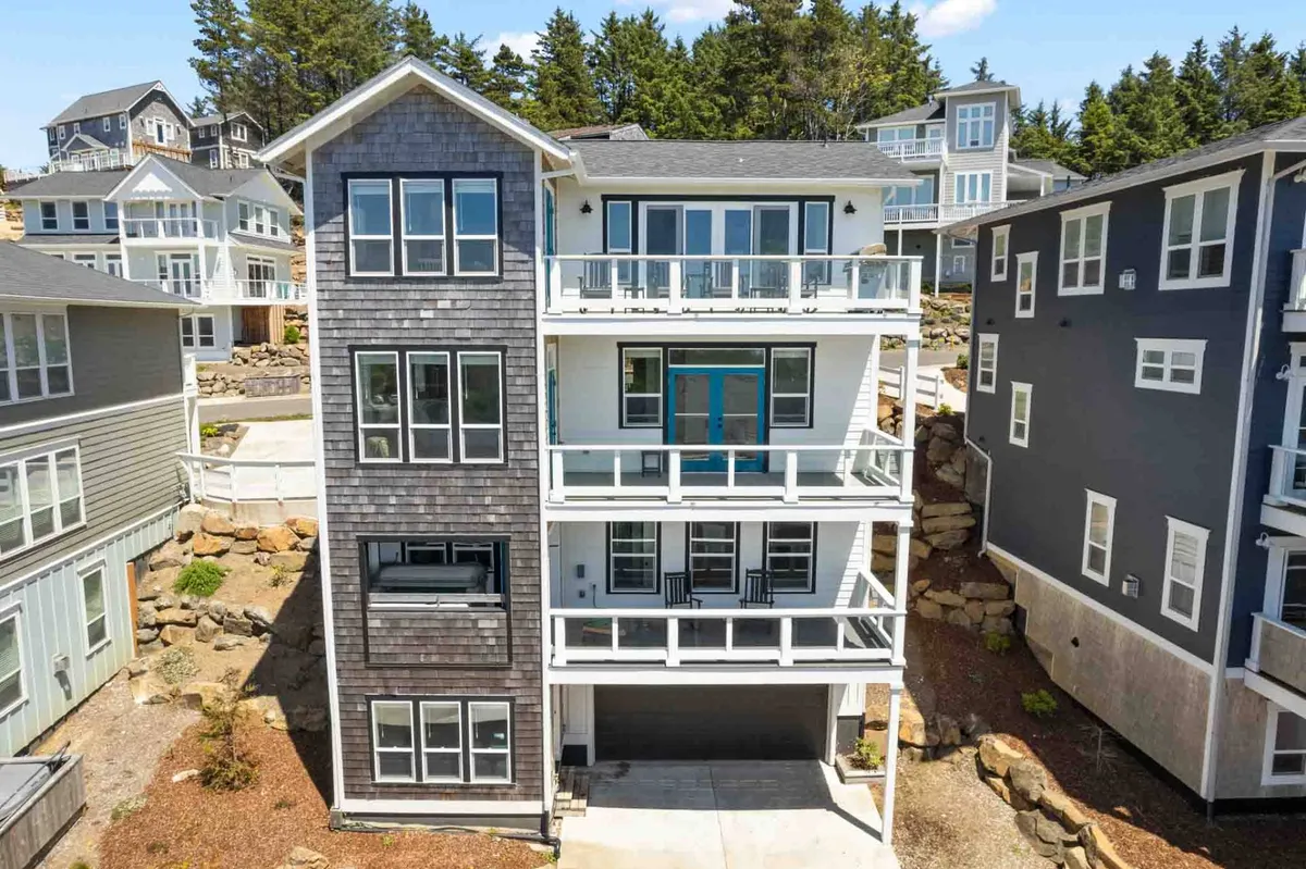 This image showcases the home's contemporary exterior, with large windows and balconies overlooking rocky landscaping. The modern architecture suggests both luxury and functional design, while inviting outdoor spaces hint at group gatherings or private relaxation.