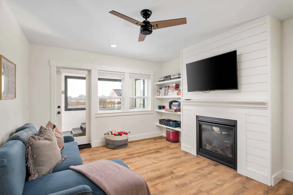 This image features a cozy living area with a comfortable sofa, a fireplace, TV, and window letting in natural light. The space is inviting and perfect for relaxing, watching movies, or spending time together as a group.
